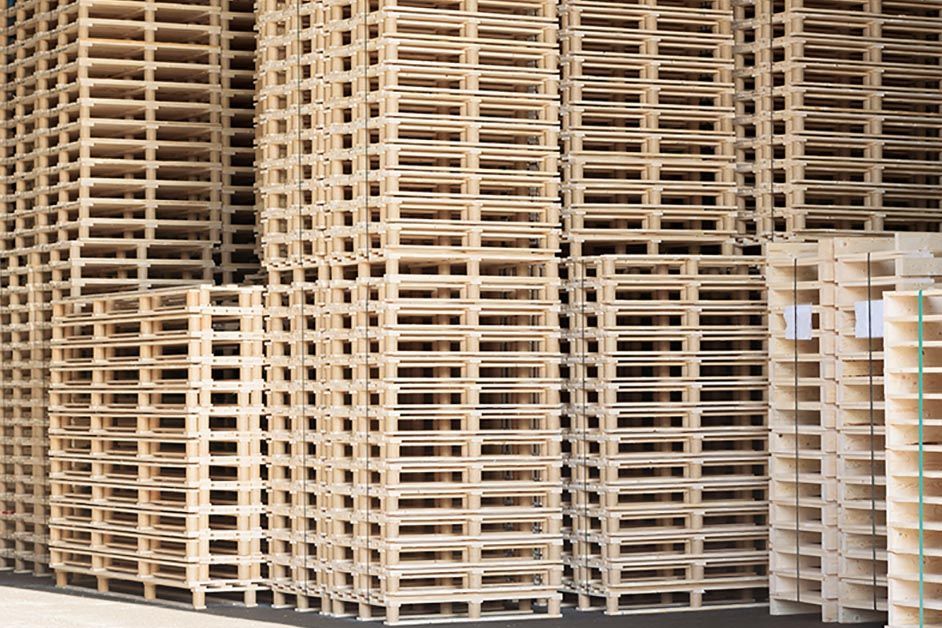 A truck filled with lots of wooden pallets is parked in a parking lot.