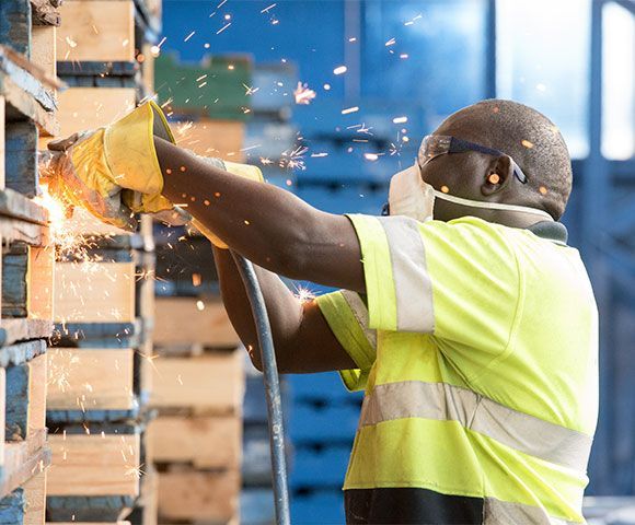 A man is cutting a piece of wood with a grinder in a factory. A man is cutting a piece of wood with a grinder in a factory.