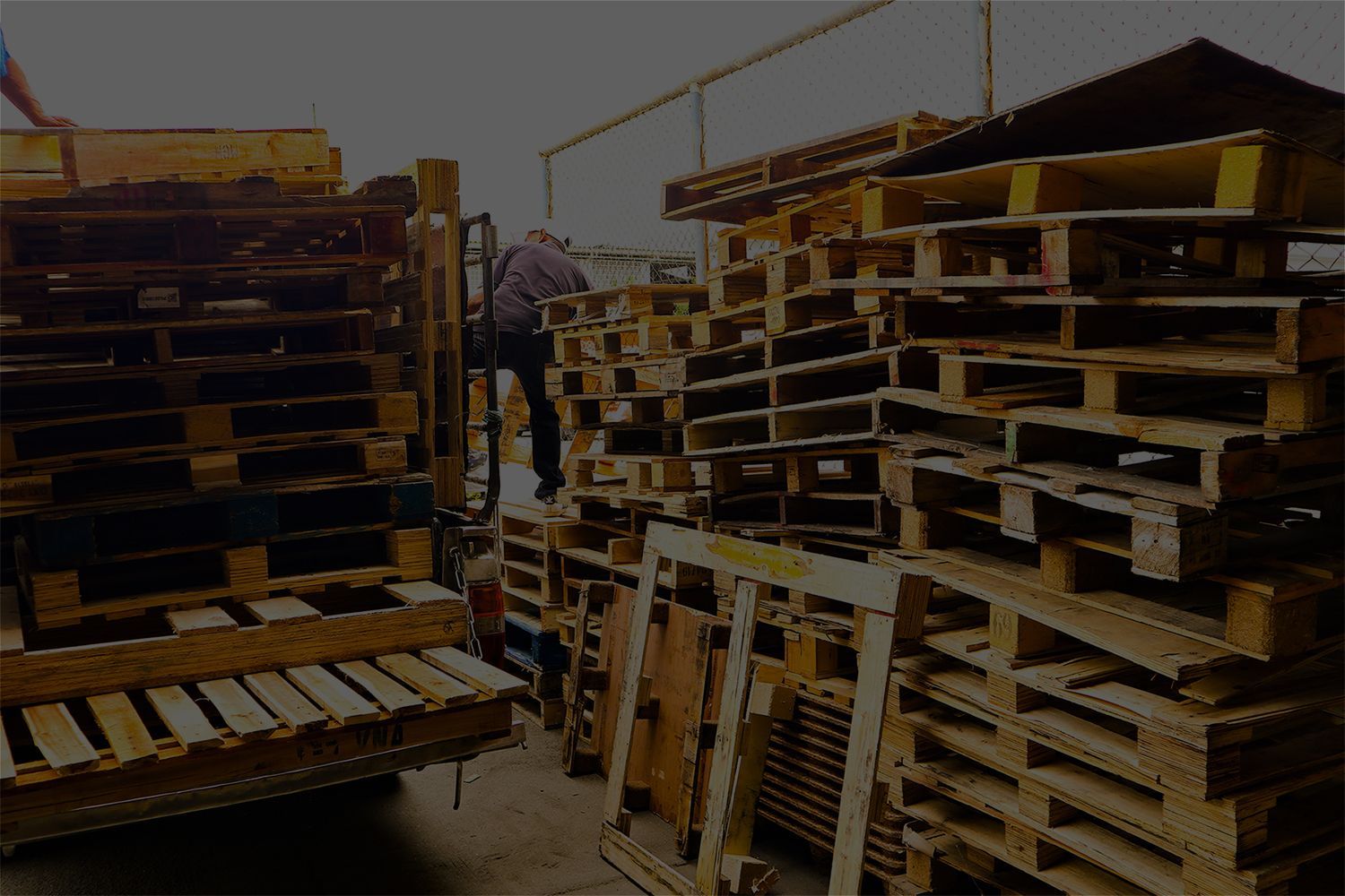 A pile of wooden pallets are stacked on top of each other in a warehouse. A pile of wooden pallets are stacked on top of each other in a warehouse.