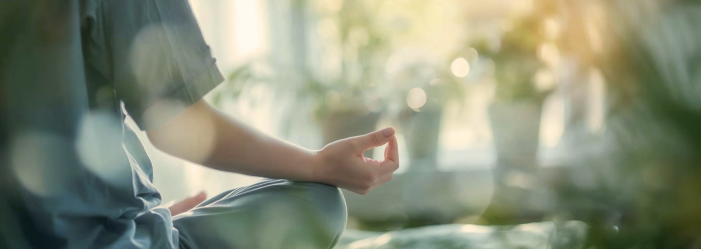 Person meditating cross-legged outdoors in soft sunlight