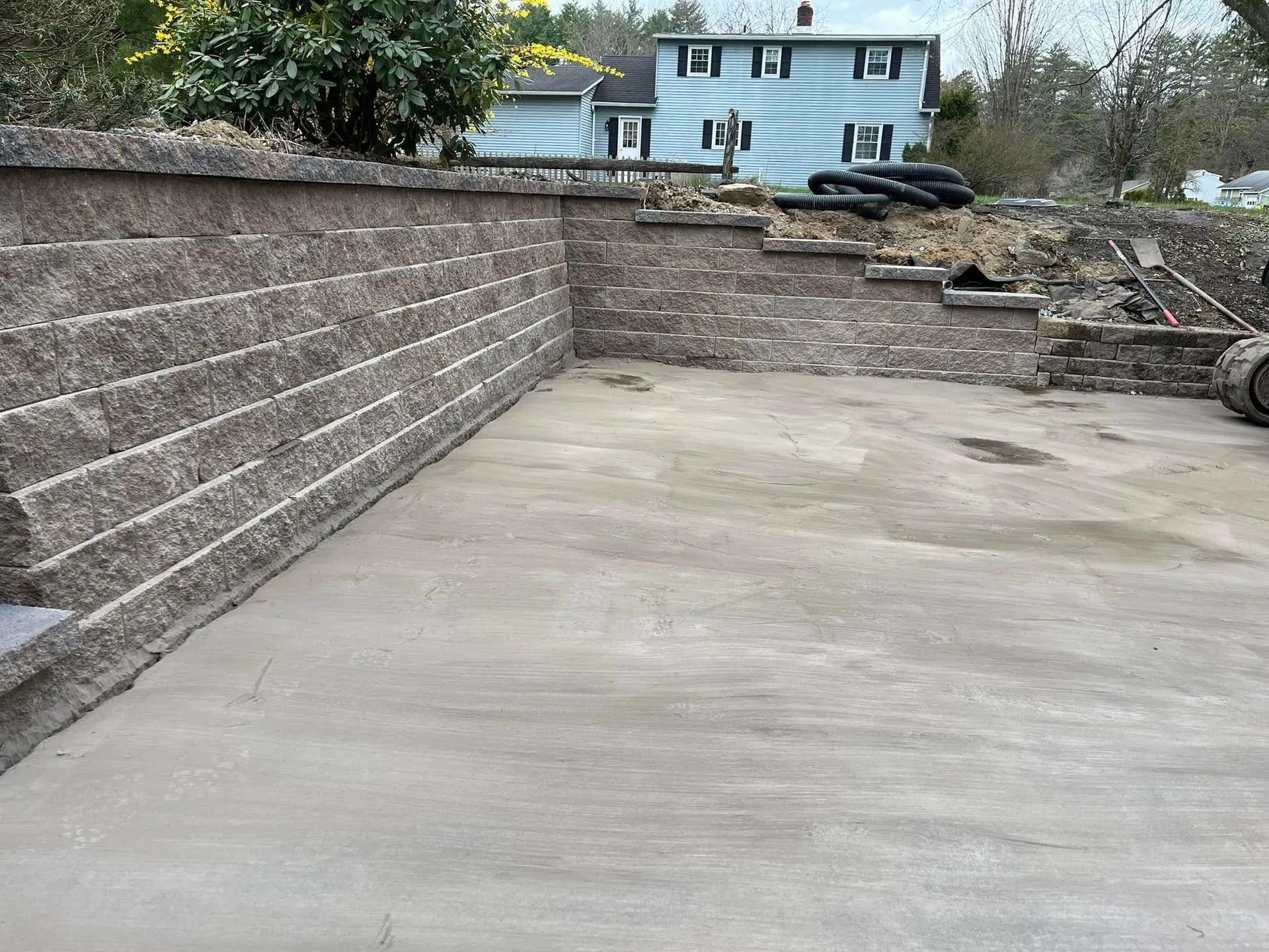 Concrete driveway beside retaining walls leading to a house in the background