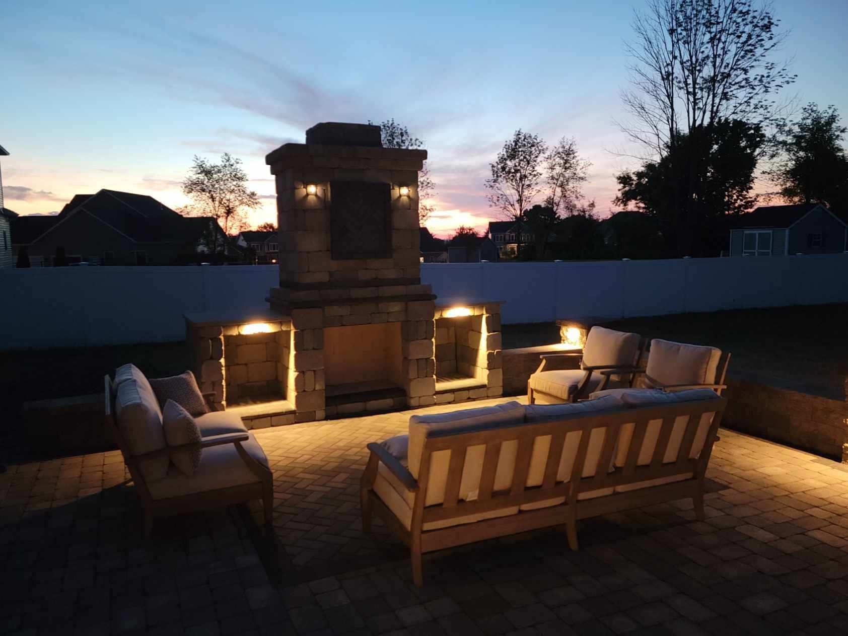 A patio with a fireplace and a couch at night