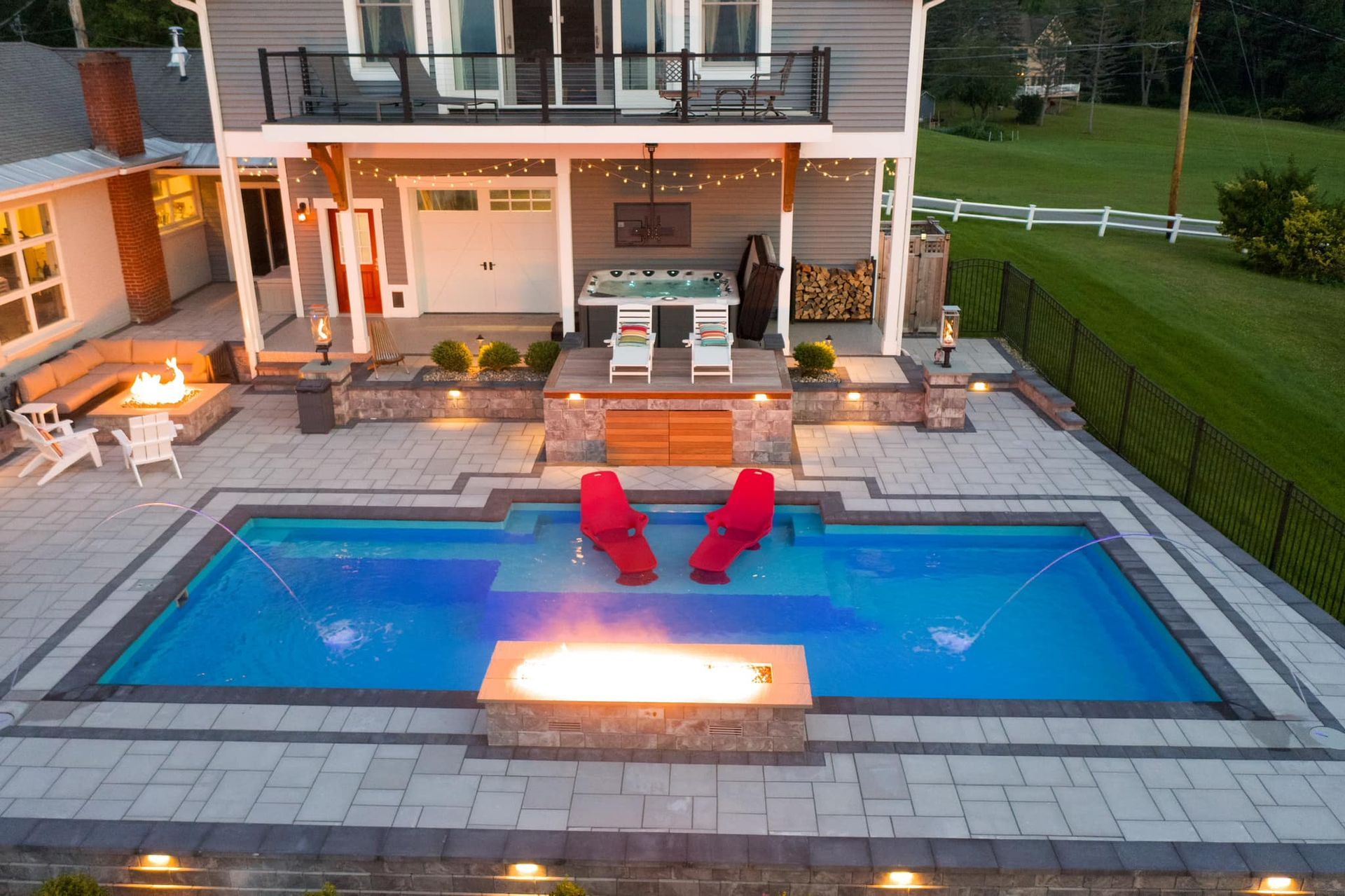 An aerial view of a large swimming pool in front of a house