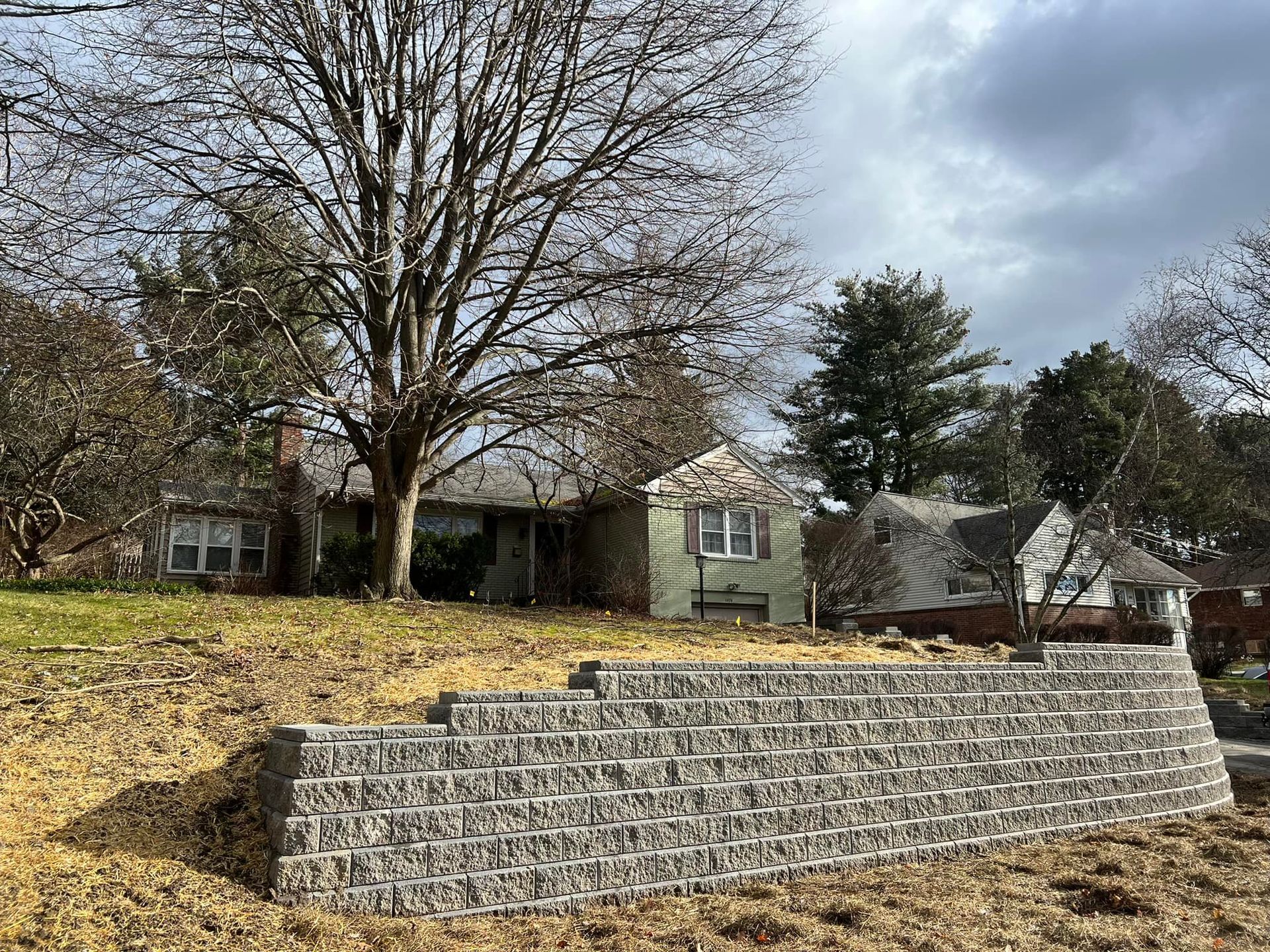 A house is sitting on top of a hill next to a brick wall.