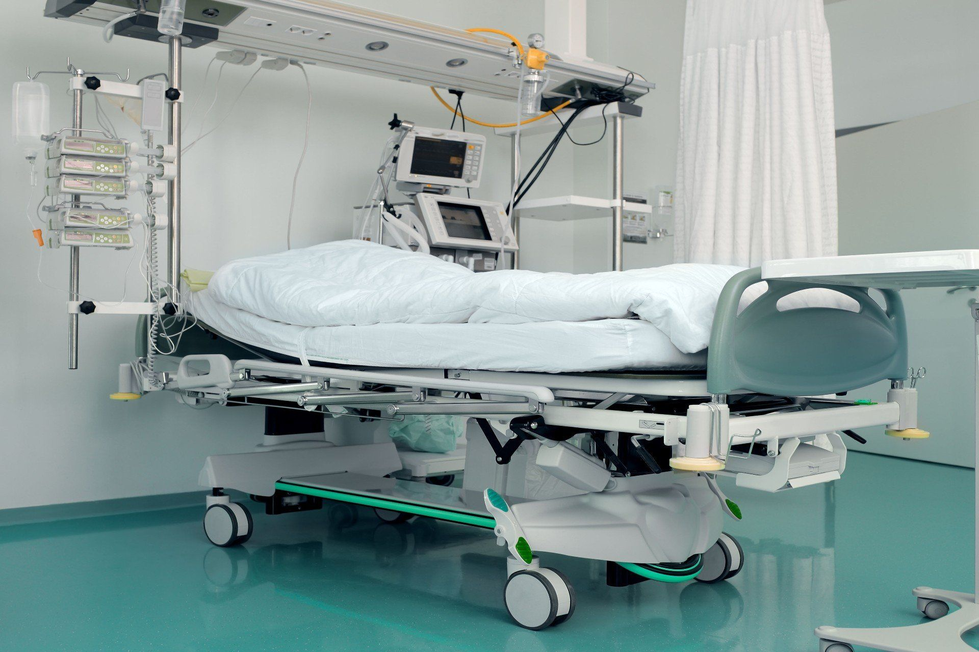An empty hospital room with a bed and a table.