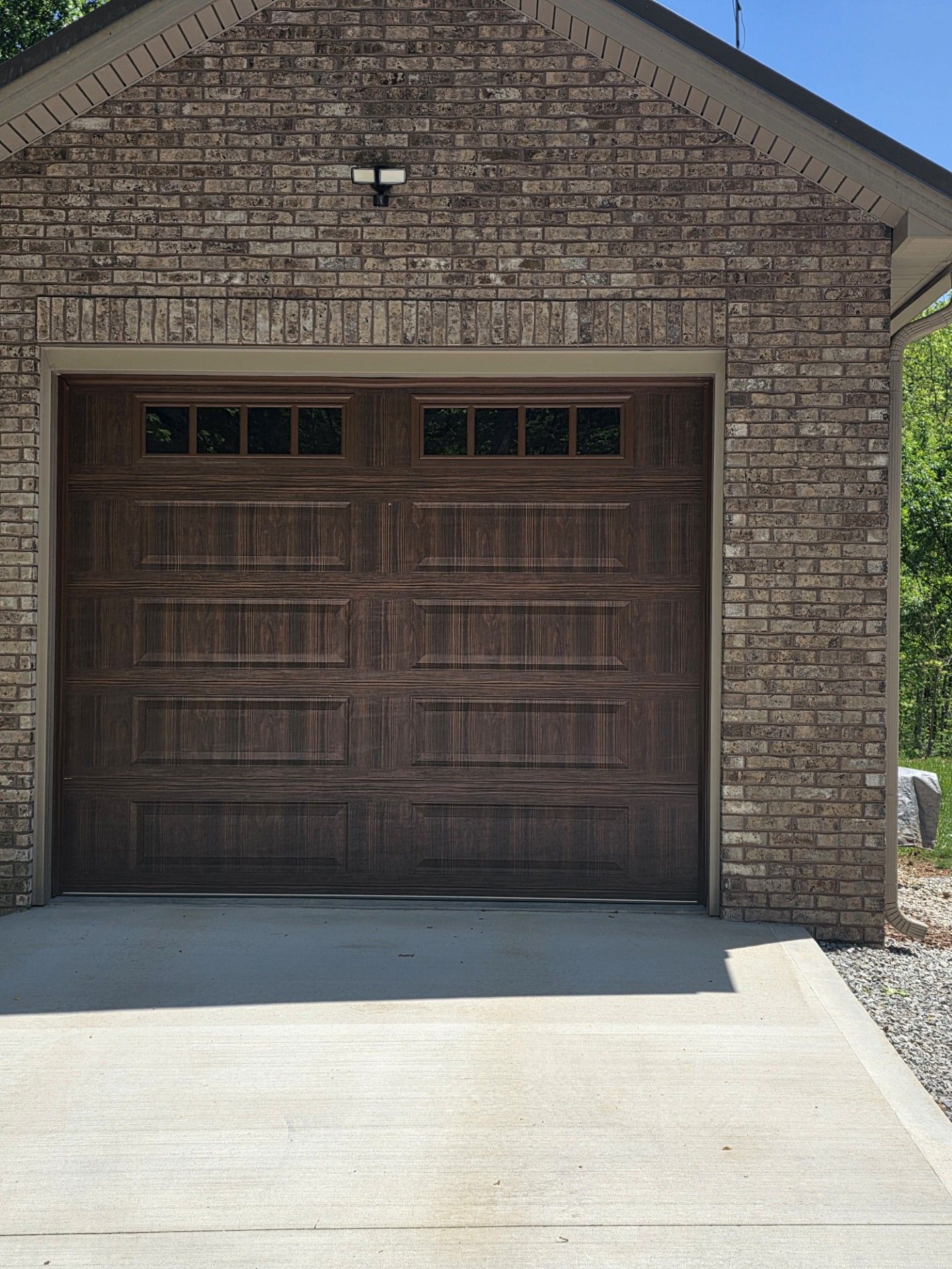 Closed brown wooden garage door in a brick house driveway
