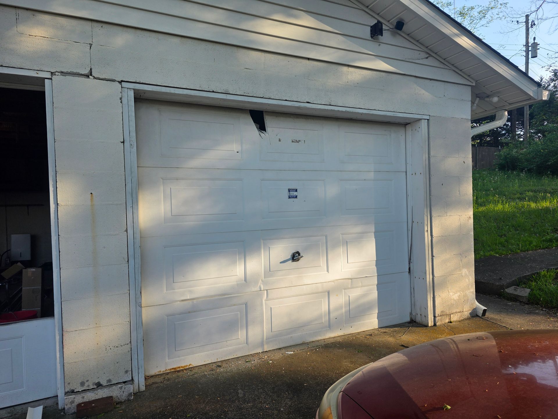 White garage door on a small detached garage with a red car parked in front.