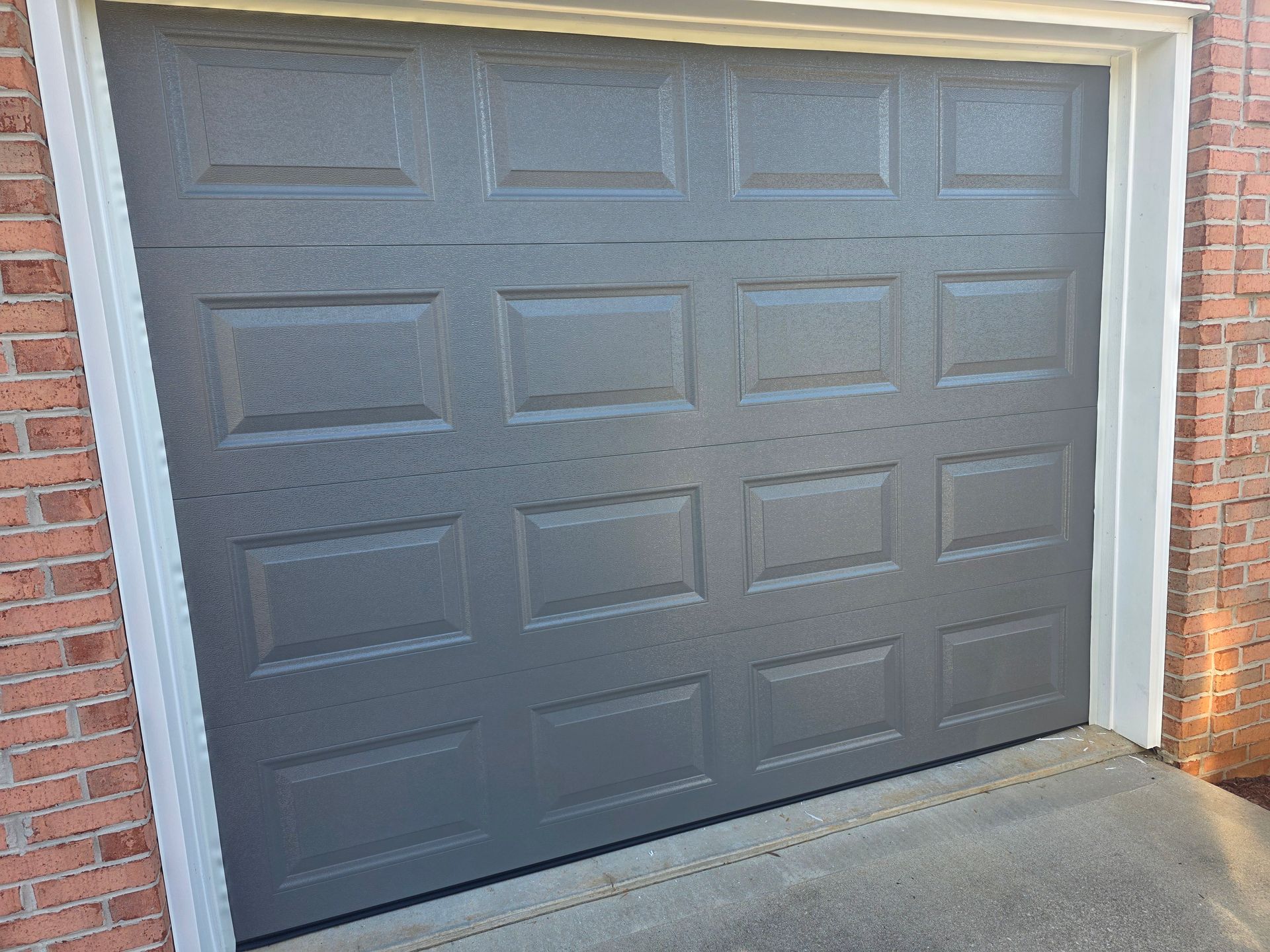 Closed dark gray garage door in a brick exterior wall