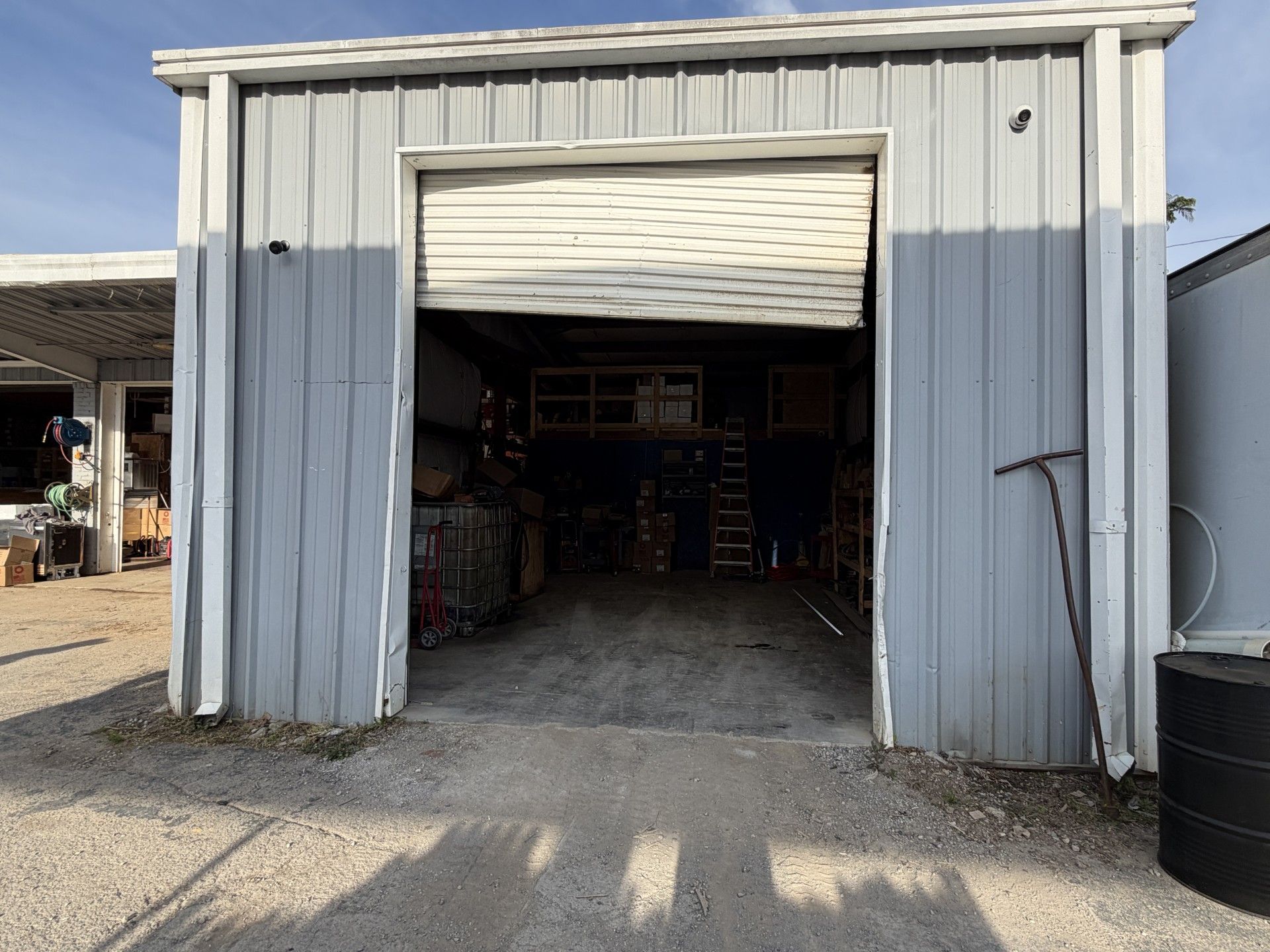 Open garage-style storage shed with a partially raised roll-up door and boxes inside