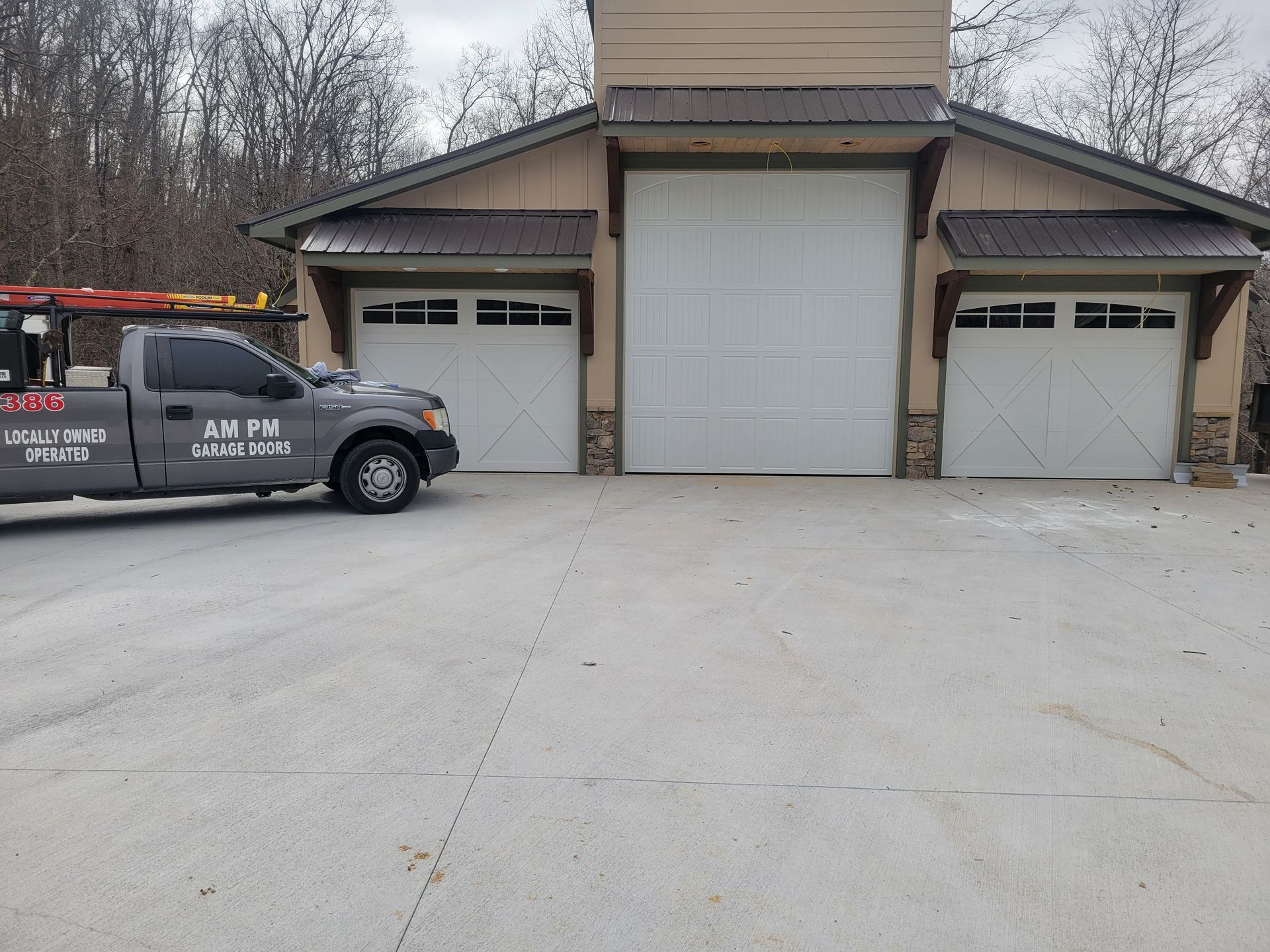 Truck parked in front of a building with three garage doors and a concrete driveway