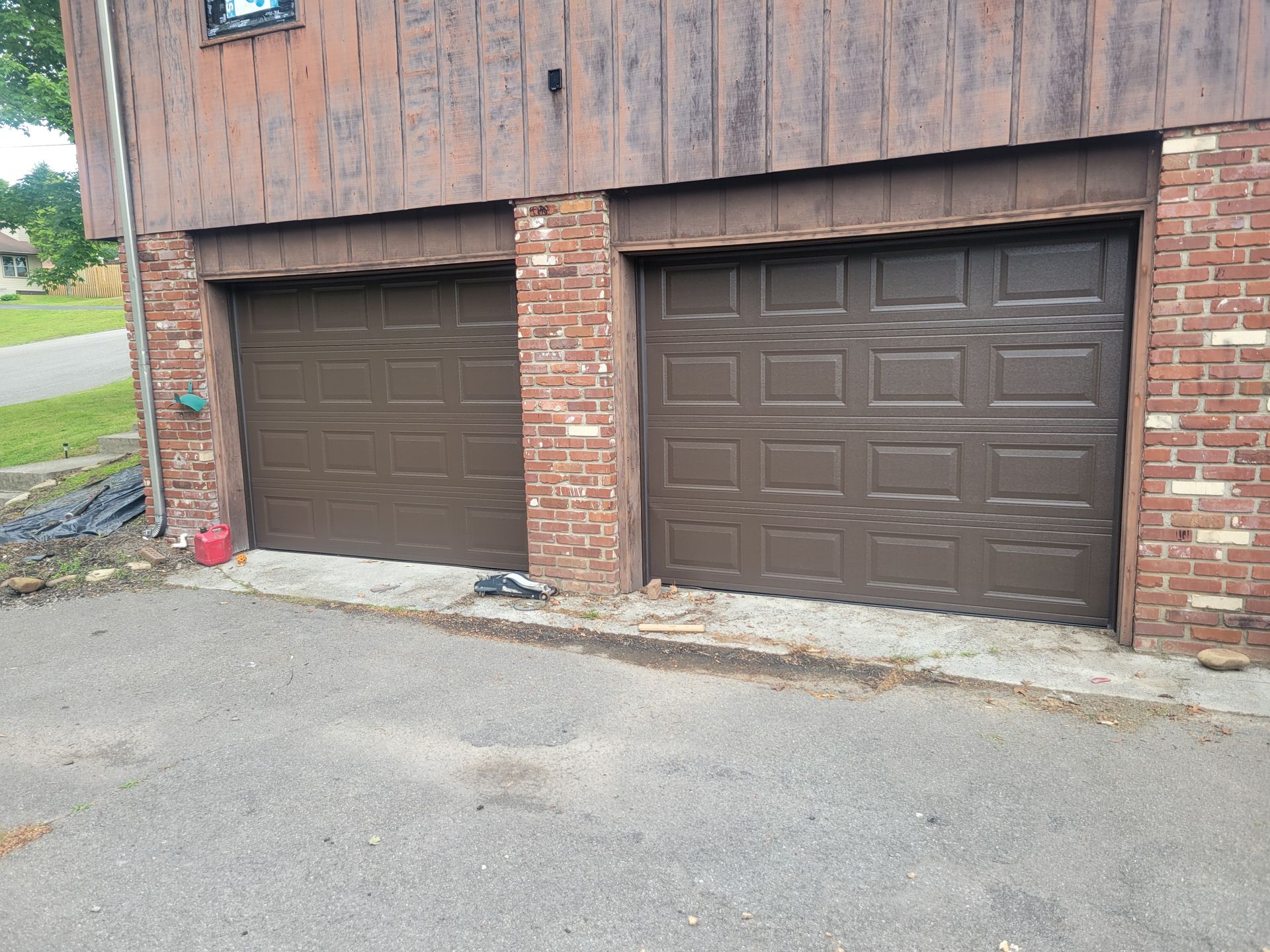 Two brown garage doors beneath a weathered wooden building exterior