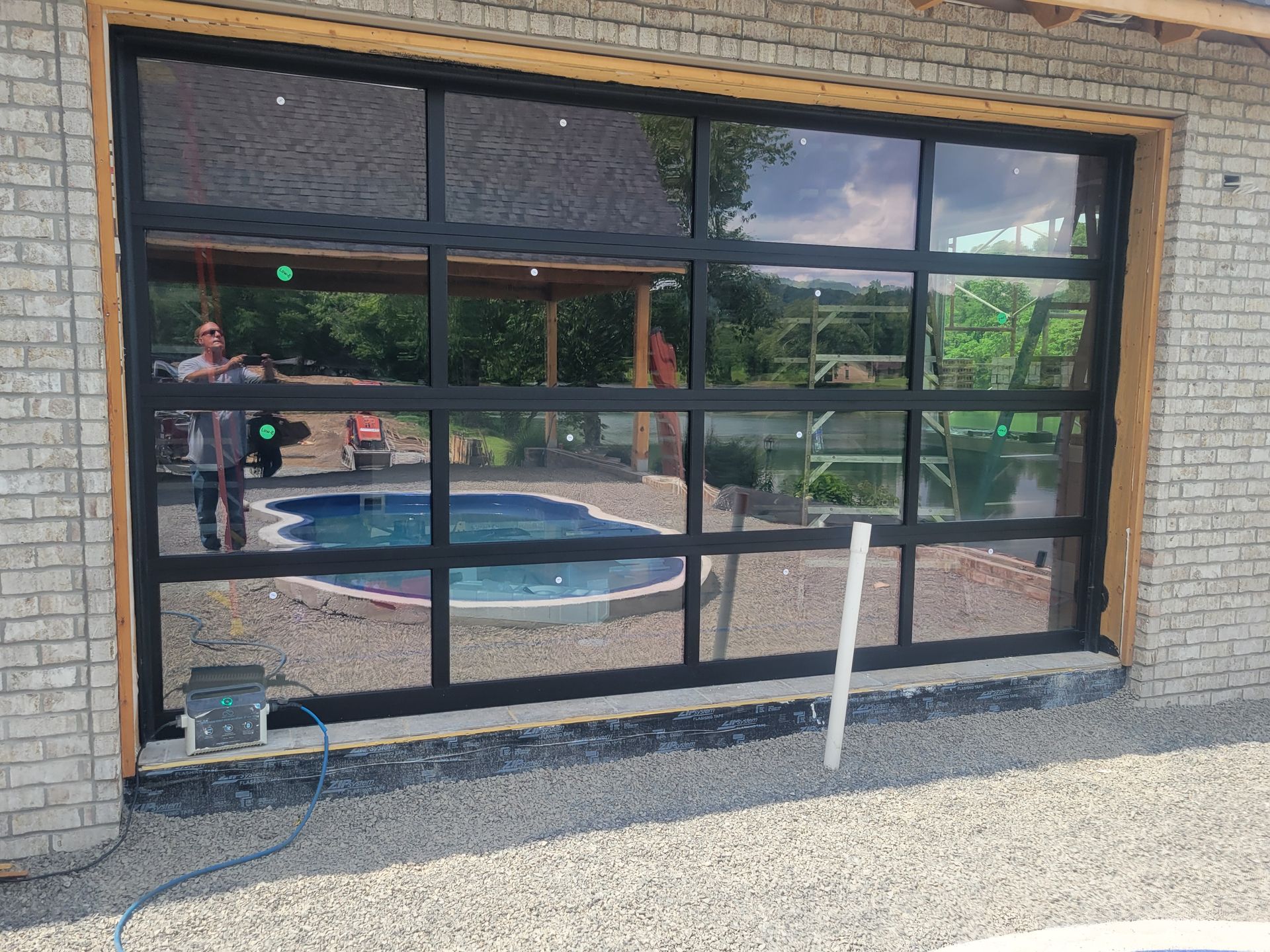 Brick building with large black-framed windows reflecting an outdoor pool and patio.