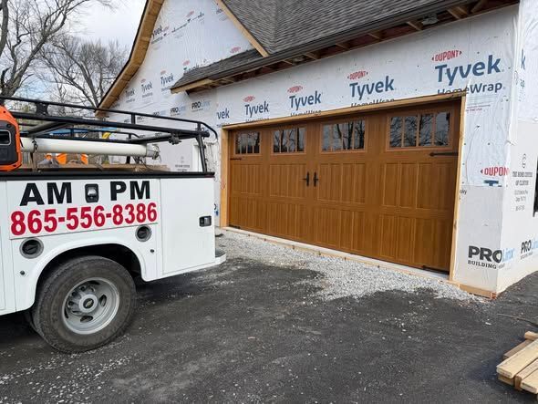 White AM PM utility truck beside a house under construction with Tyvek wrap and brown garage doors