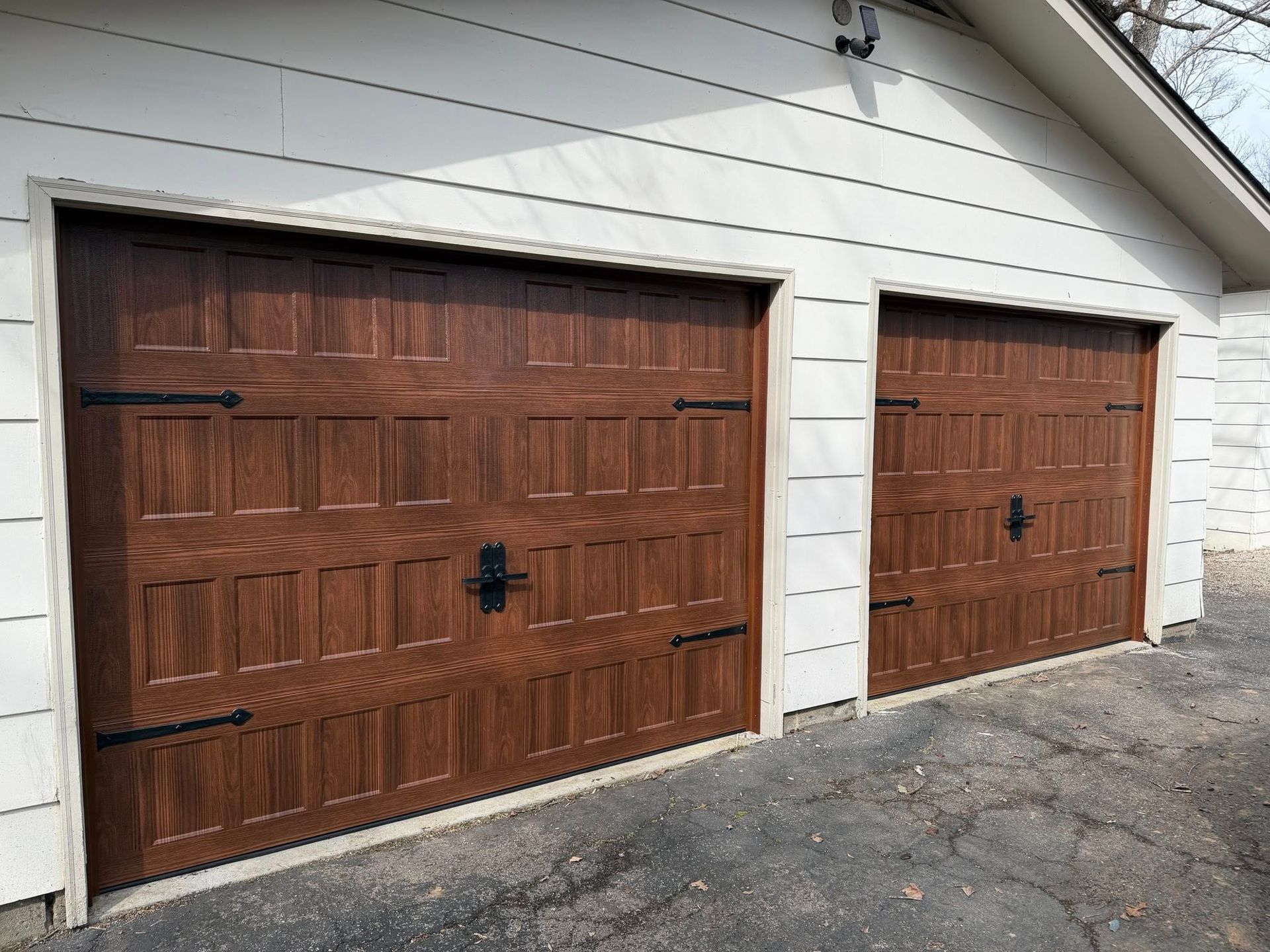 Two brown paneled garage doors on a white house exterior