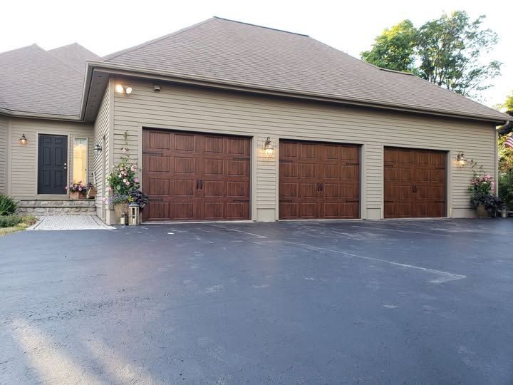 Suburban house exterior with three garage doors and a wide black driveway