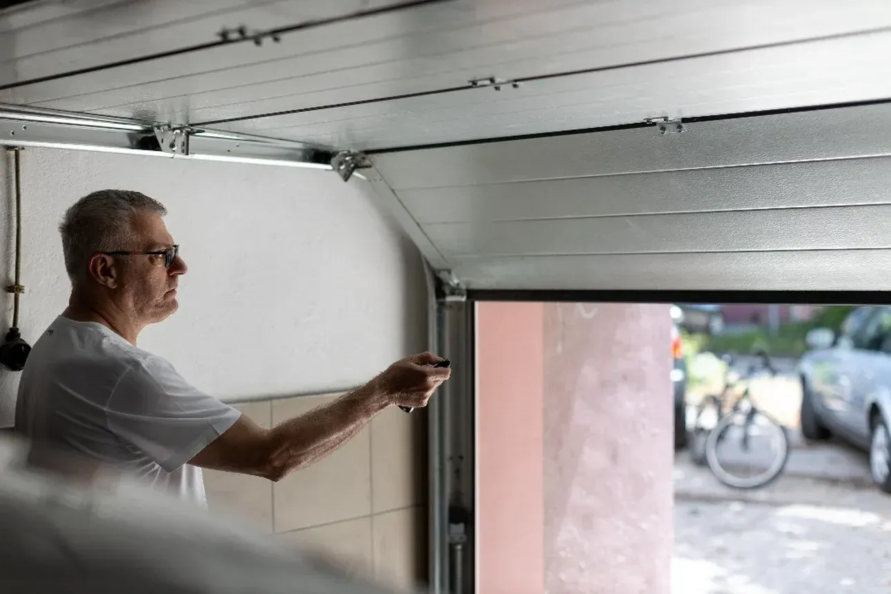 Man pointing at a garage door while a bicycle is visible outside in daylight