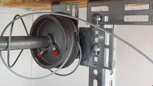 Spool of cable mounted on a metal wall bracket with a cable running across it
