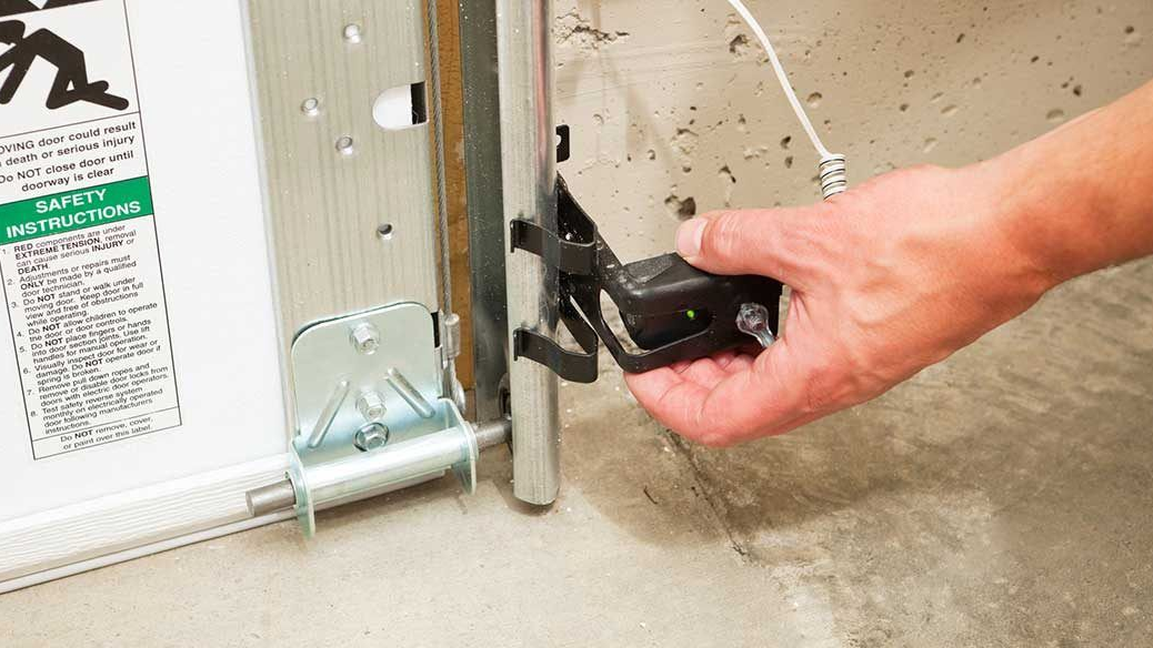 Hand attaching a black hinge latch to a metal gate with a wrench