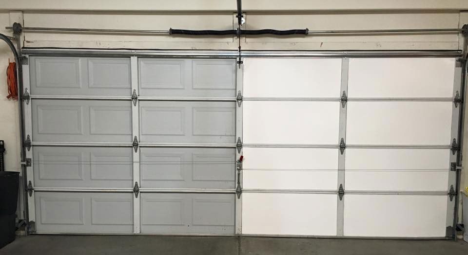 Double garage with two white sectional doors and a beige wall.