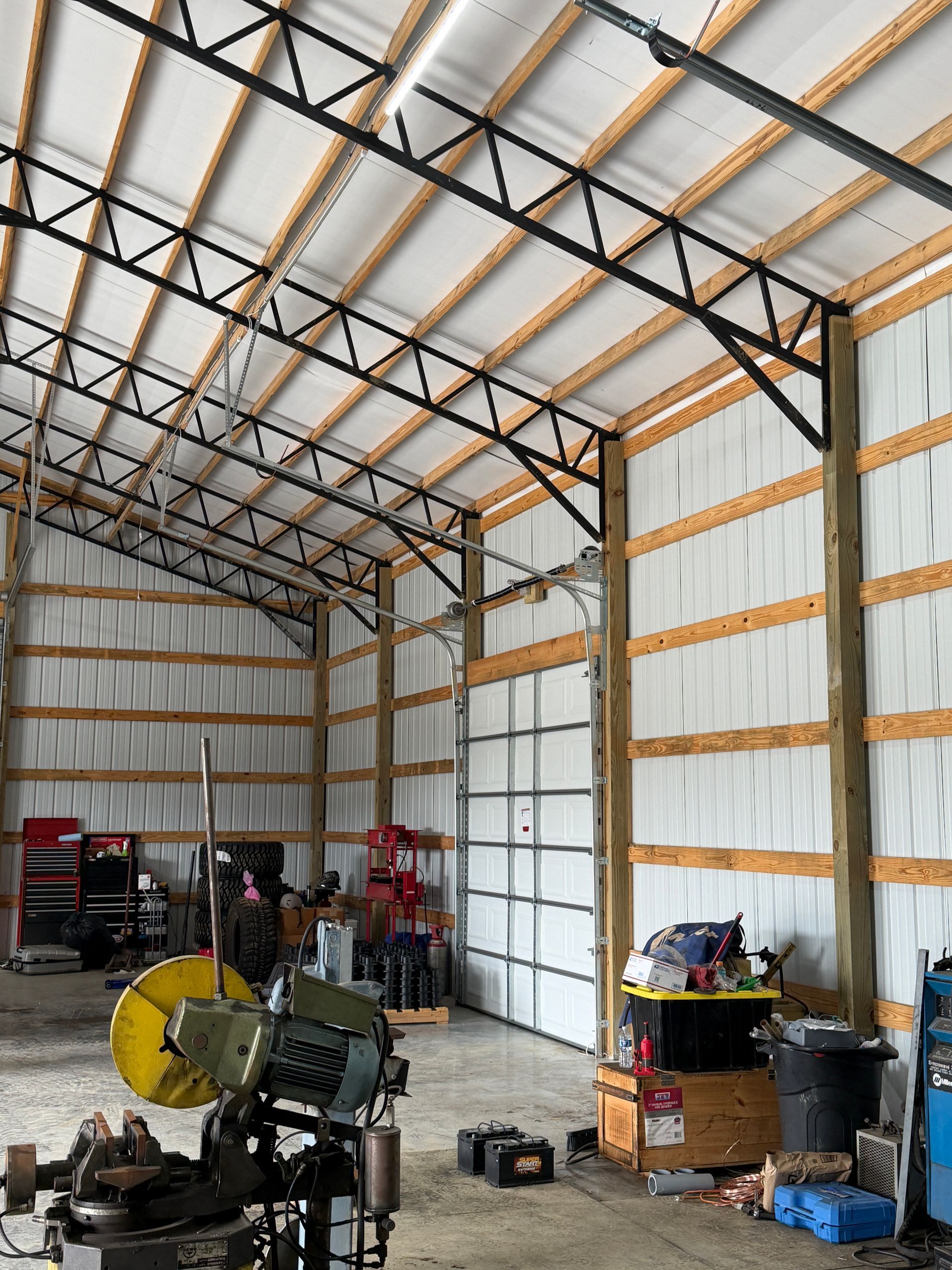 Interior of a metal workshop with corrugated walls, exposed trusses, and tools stored along the sides.