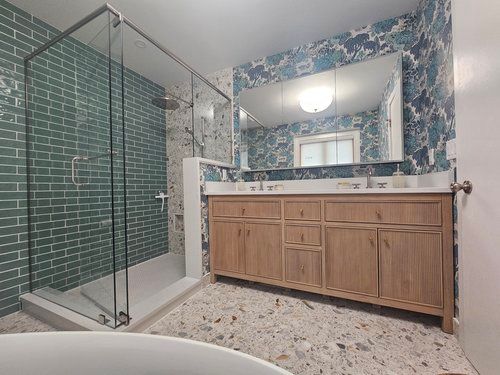 A bathroom with two sinks , a walk in shower , and a large mirror.