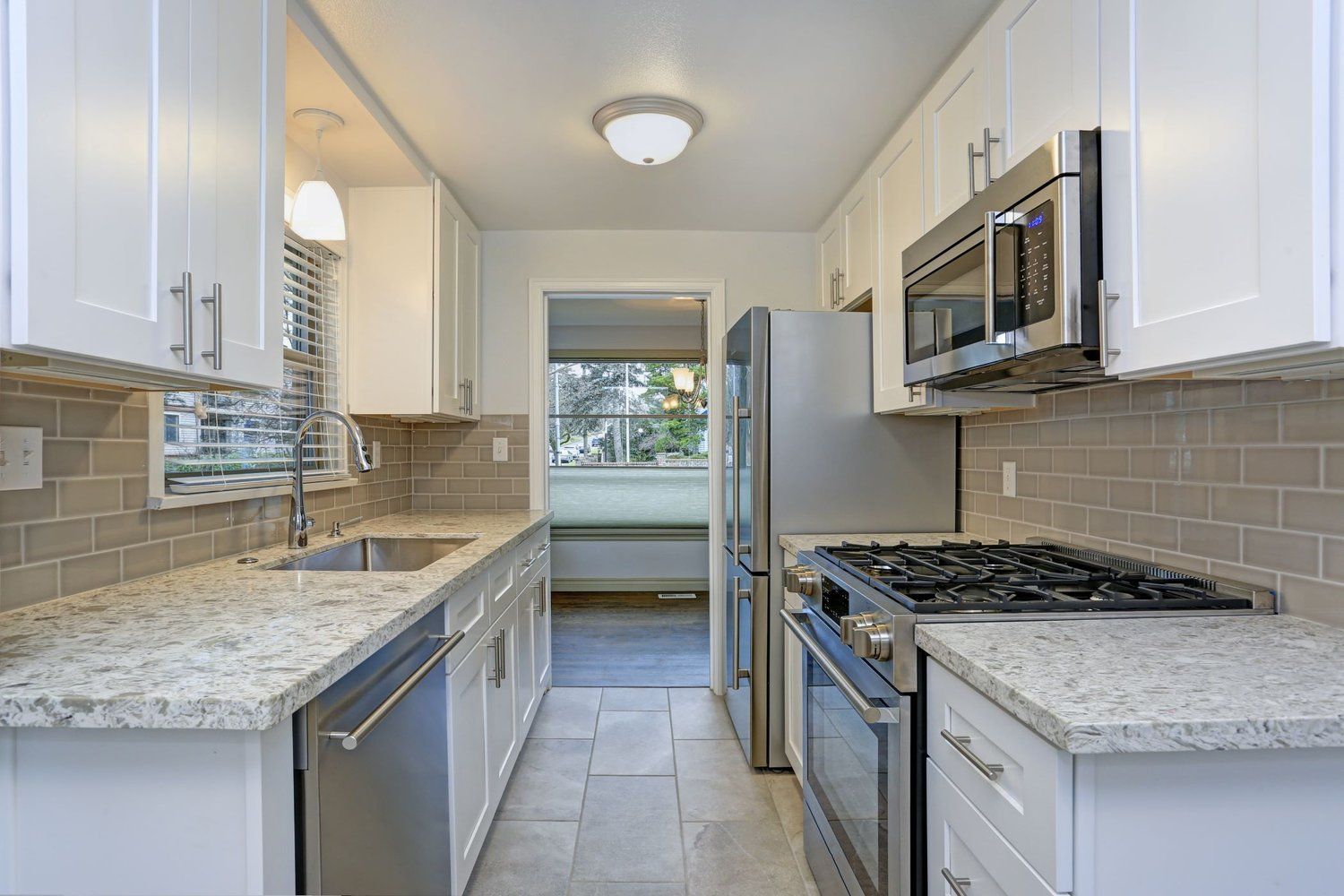 A kitchen with white cabinets , granite counter tops , stainless steel appliances and a stove.