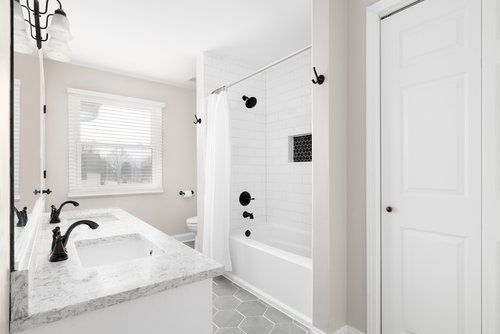 A bathroom with two sinks , a tub , and a window.