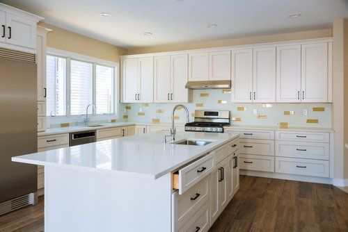 A kitchen with white cabinets , stainless steel appliances , and a large island.