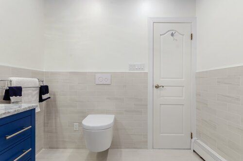 A bathroom with a toilet hanging from the wall and a blue vanity.