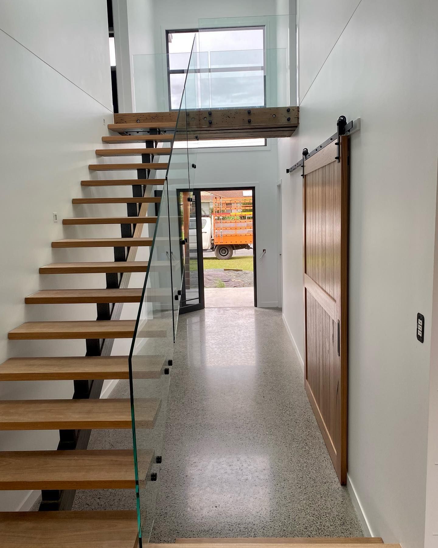A Wooden Staircase With a Glass Railing in a Hallway — Swift Glass & Aluminium In Woolgoolga, NSW