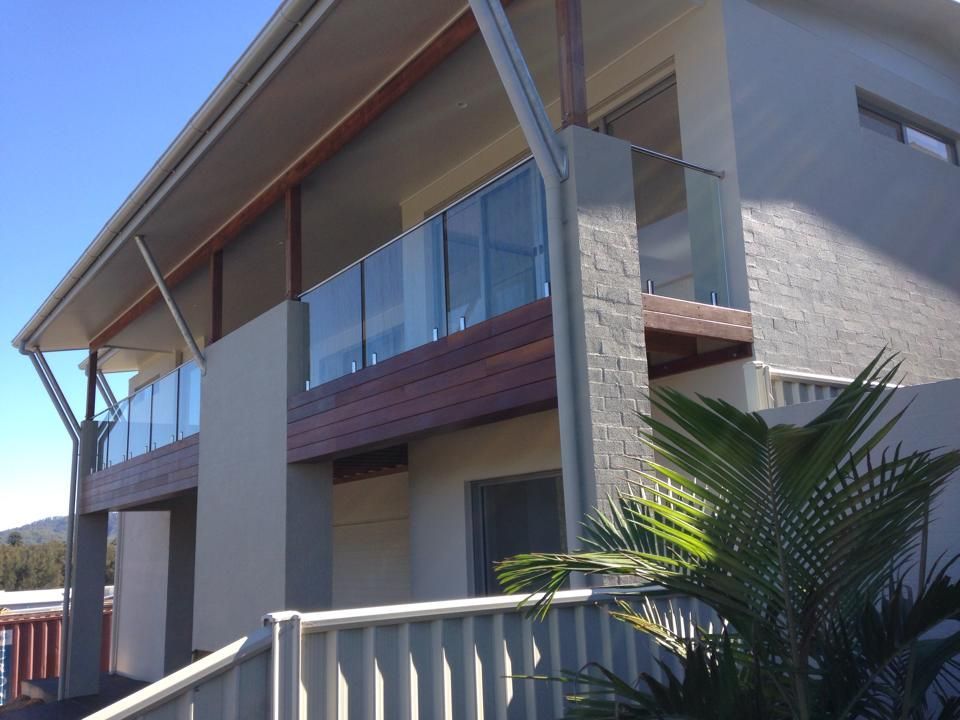 A House with a Balcony and a Palm Tree in Front of It — Swift Glass & Aluminium In Woolgoolga, NSW