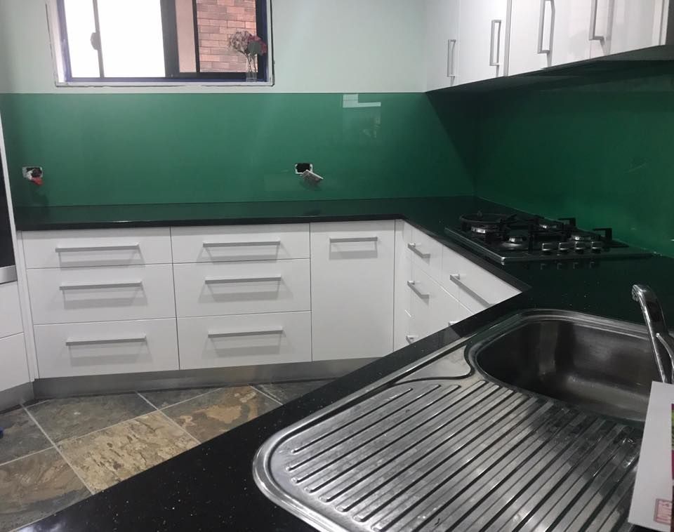 A Kitchen With White Cabinets, Black Counter Tops, a Sink and a Stove β Swift Glass & Aluminium In Woolgoolga, NSW