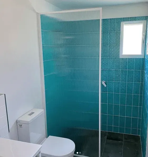 A Bathroom With a Toilet and a Shower Stall With Blue Tiles β Swift Glass & Aluminium In Woolgoolga, NSW