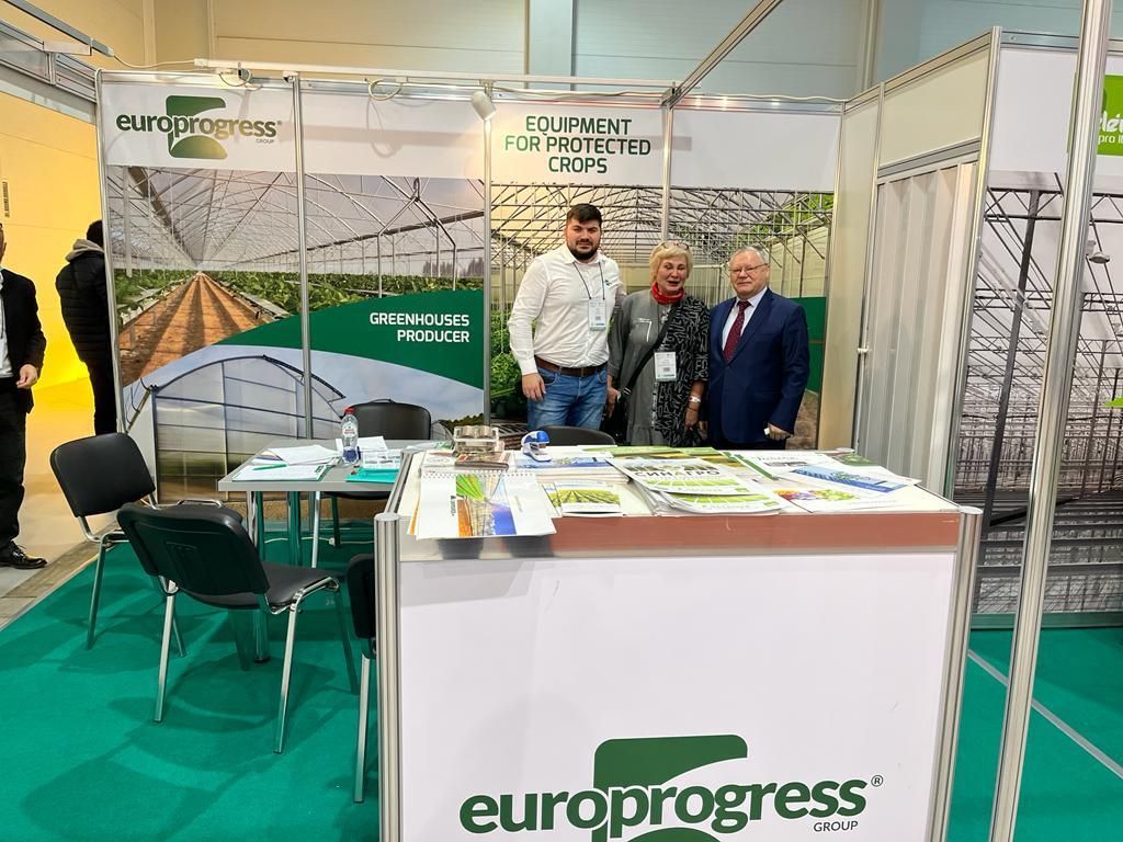 Lo stand di Europrogress a una fiera, con due uomini in piedi dietro un bancone espositivo e la grafica verde dello stand.