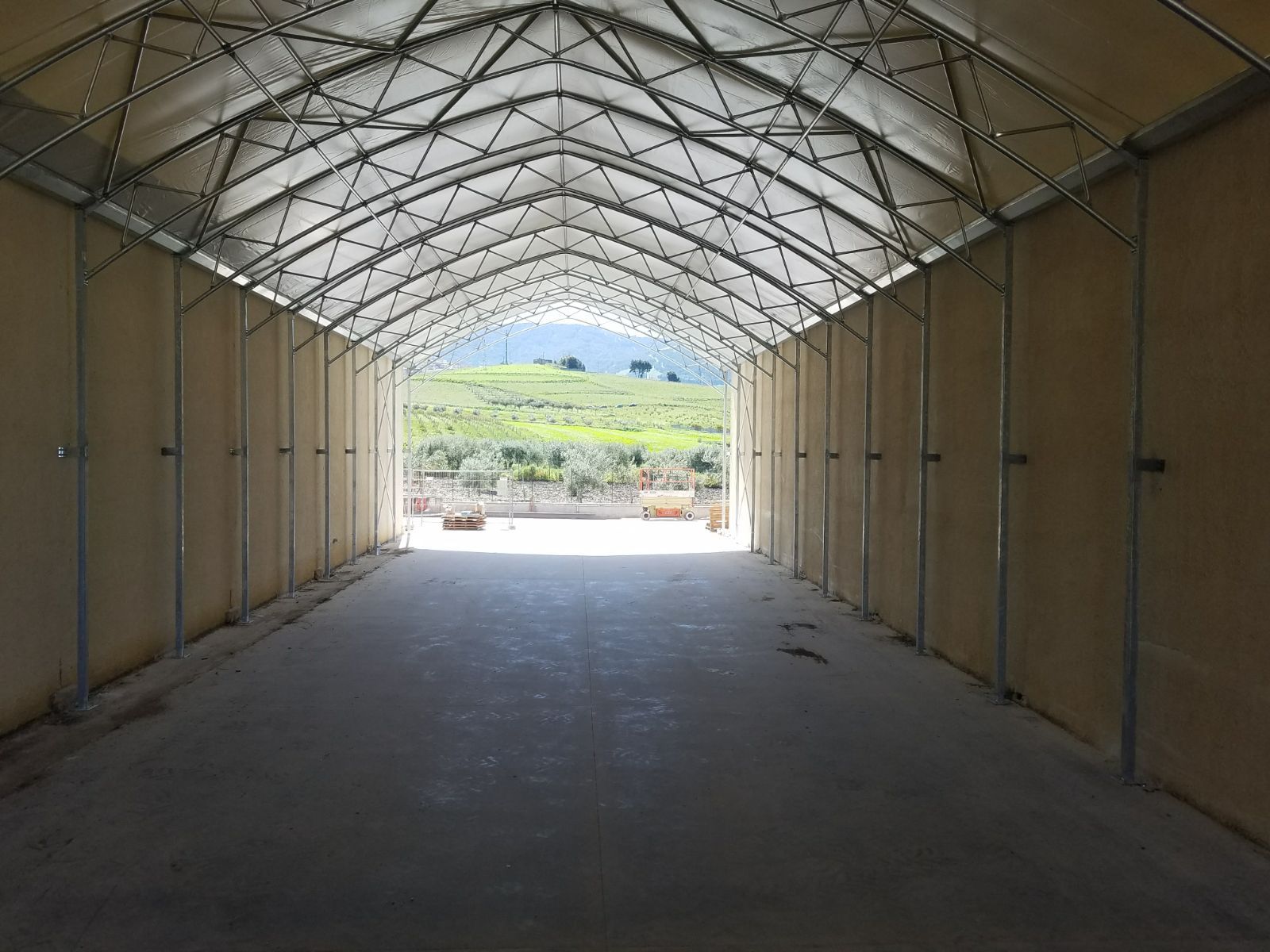 Un tunnel vuoto rivestito di tessuto conduce a un luminoso paesaggio esterno in lontananza.