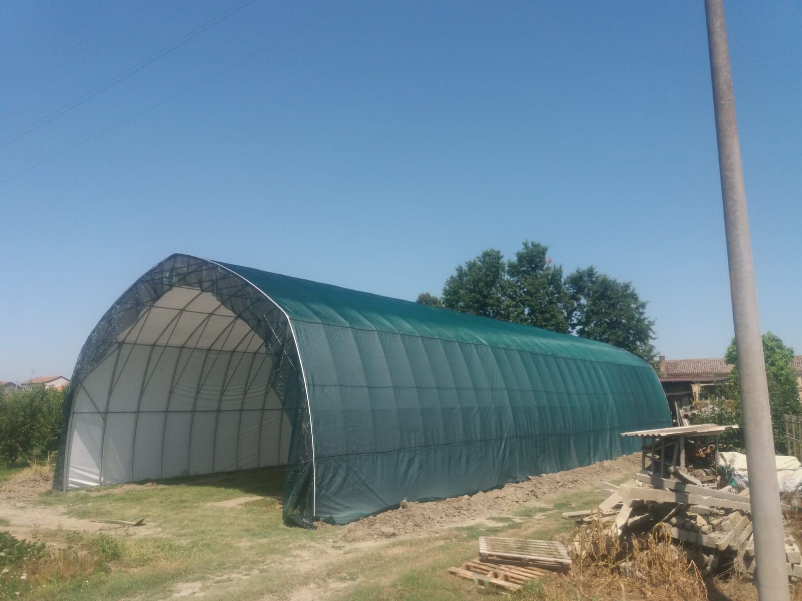 Serra a tunnel ad arco verde in un campo di campagna sotto un cielo azzurro limpido