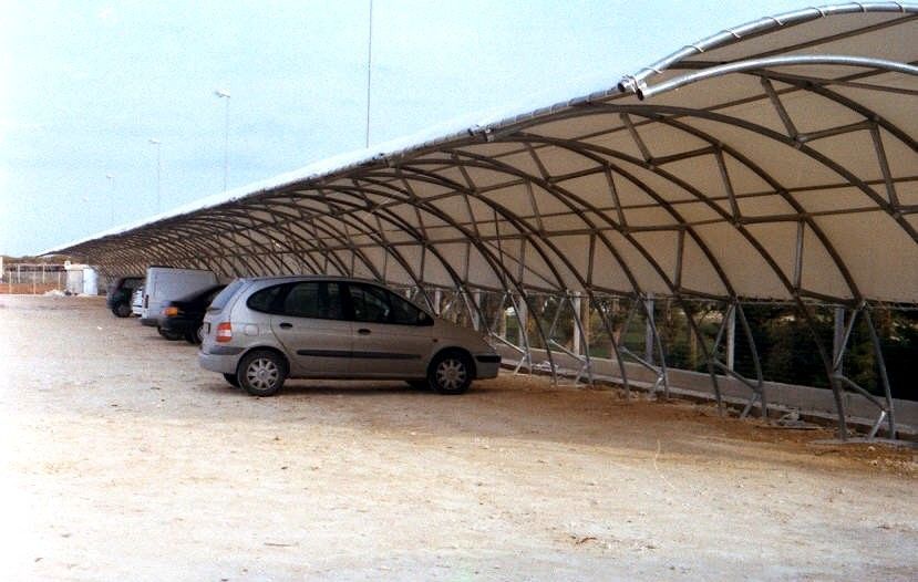 Auto parcheggiate sotto un grande riparo coperto su un lotto sabbioso
