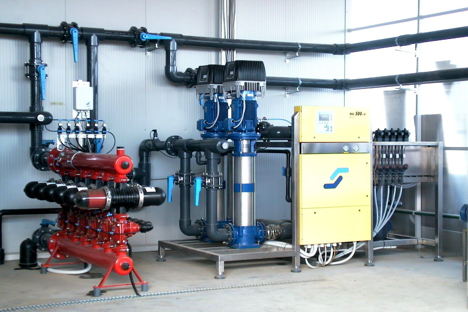 Macchinari industriali con attrezzature blu, rosse e gialle in un locale di servizio