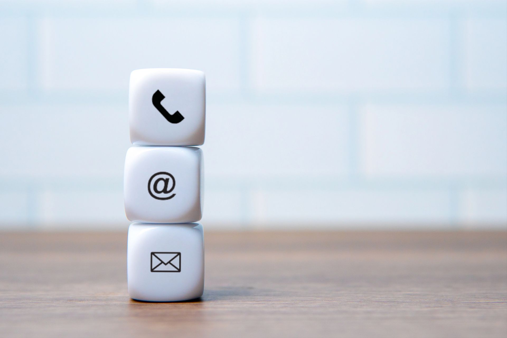 Zuccheri bianchi impilati con icone di telefono, @ ed email su uno sfondo di scrivania