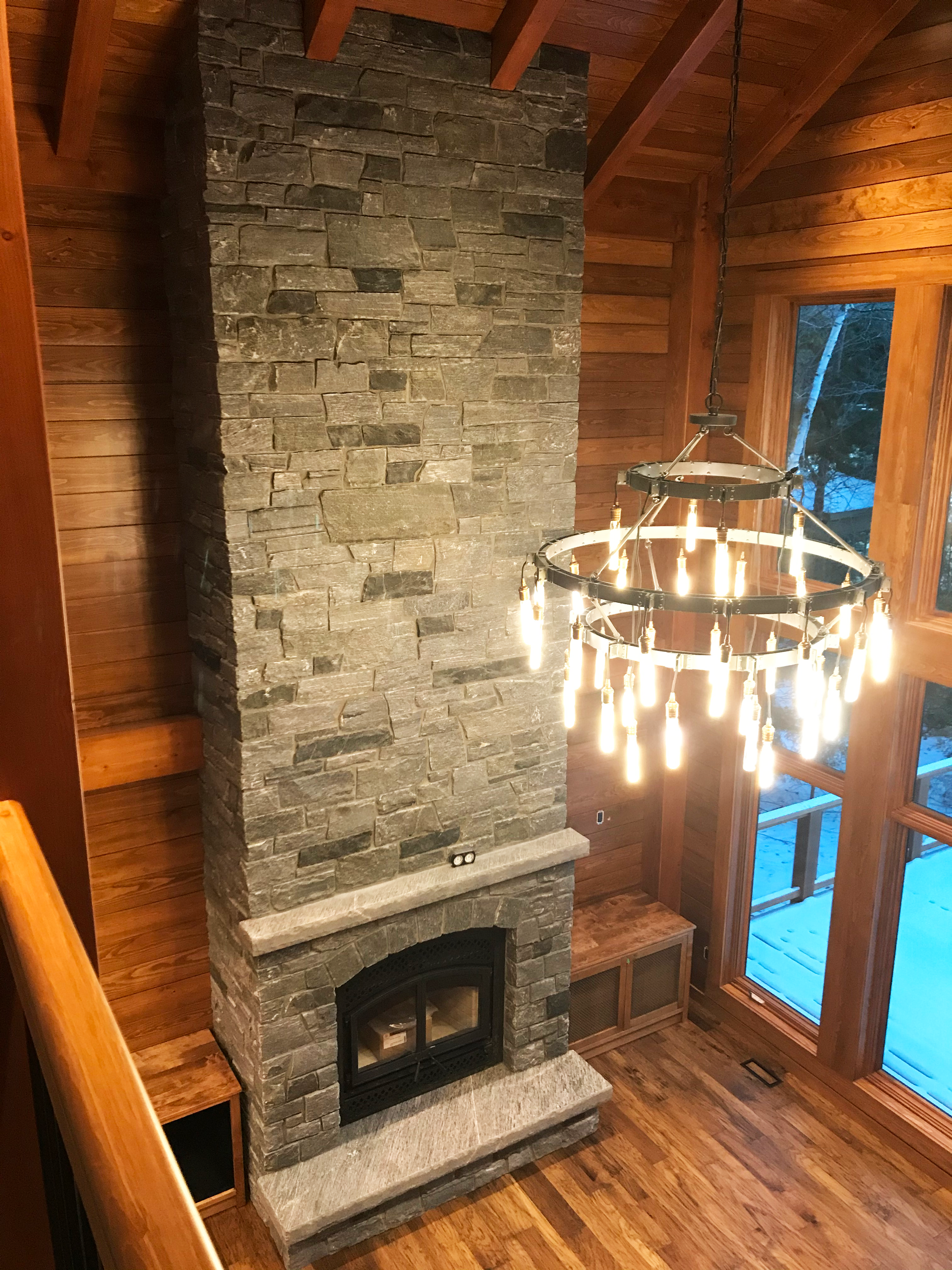 View from balcony of a tall standing, stone fireplace.