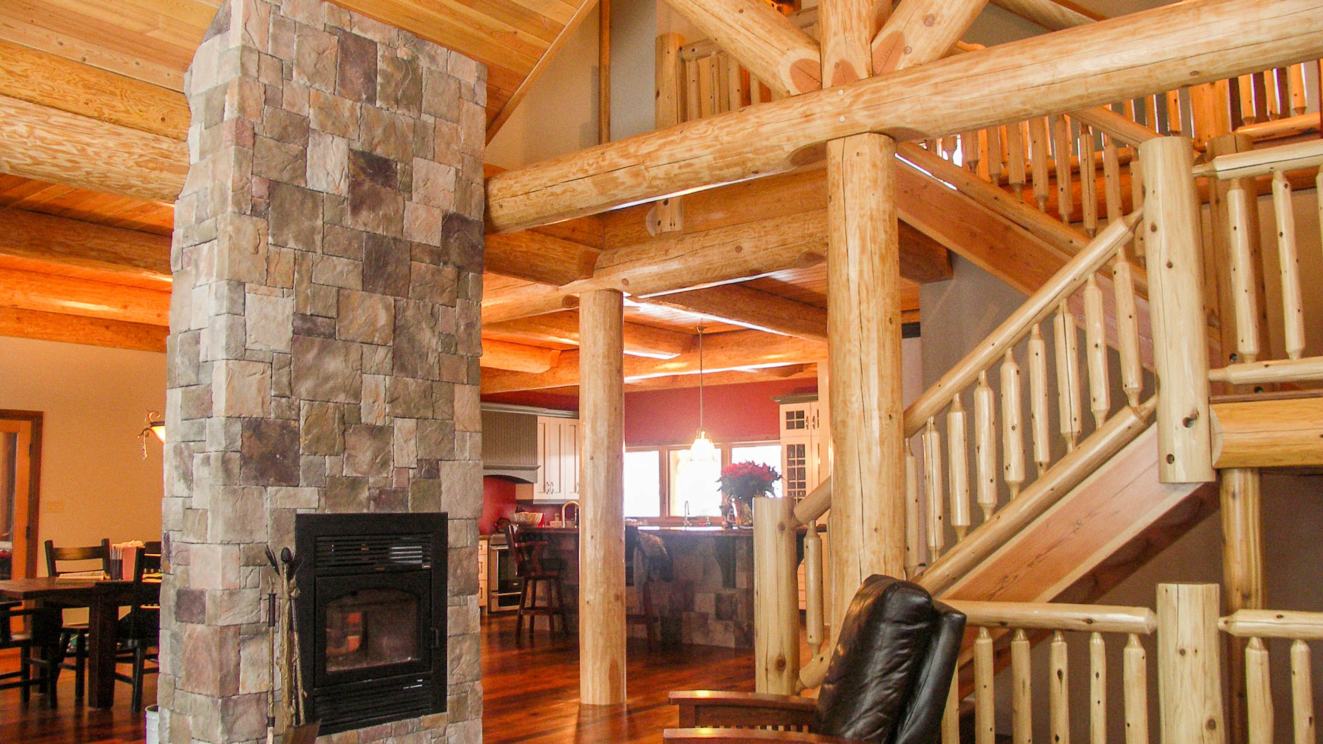 Interior of a large log cottage, showing log beams and hand-carved staircase .