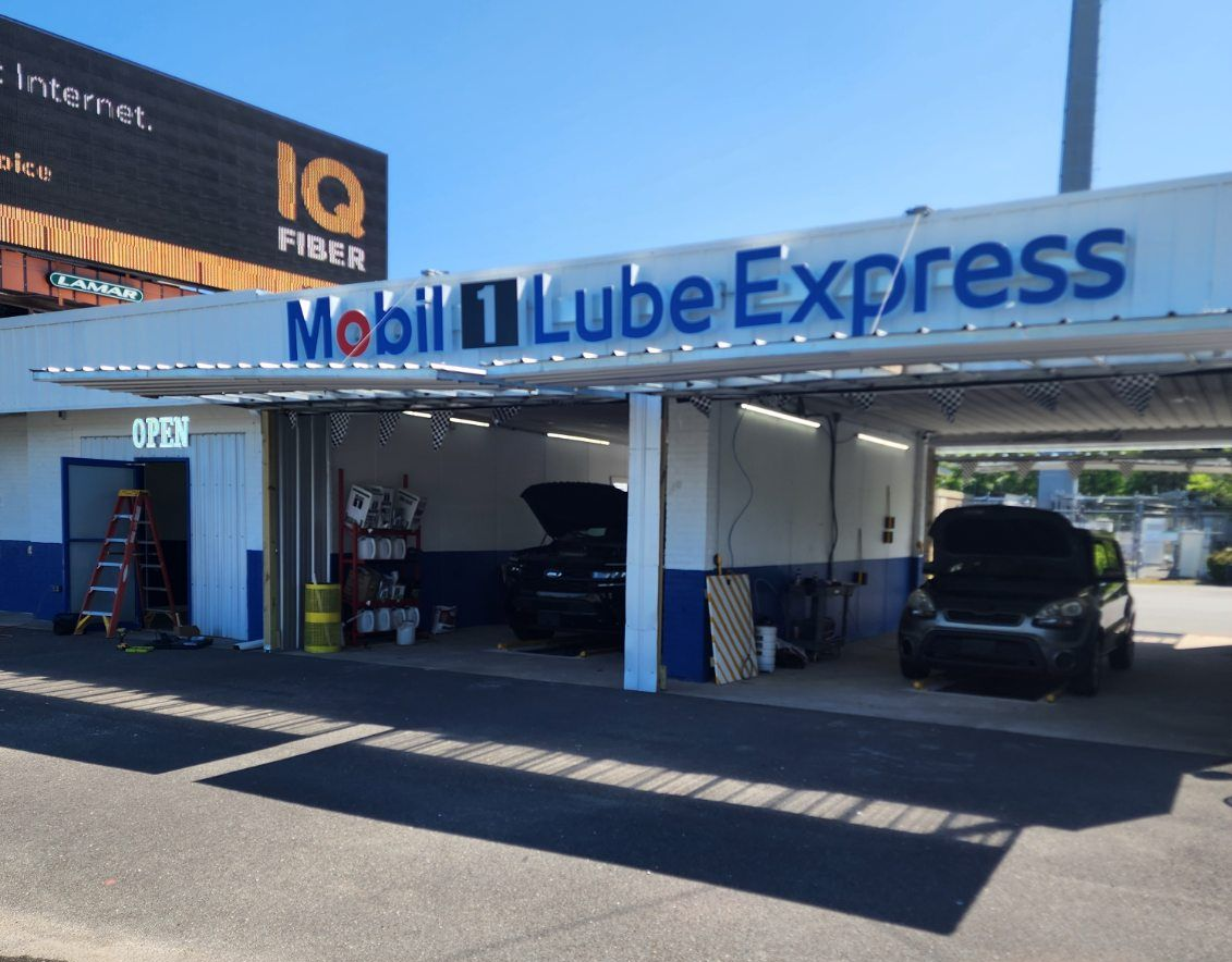 Mobil 1 Lube Express auto service bays with cars under a blue-and-white canopy