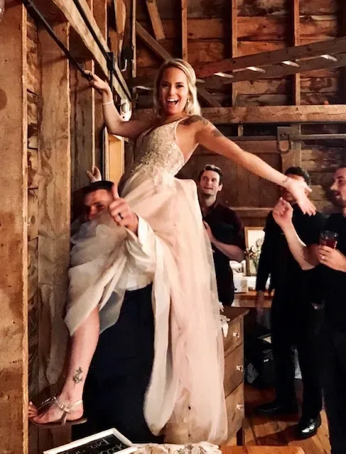 A woman in a wedding dress is standing on a man 's shoulders