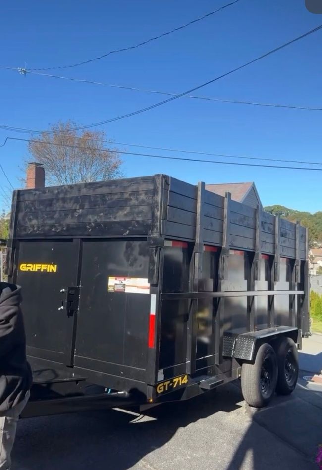 Black dump truck parked on a street under a clear blue sky