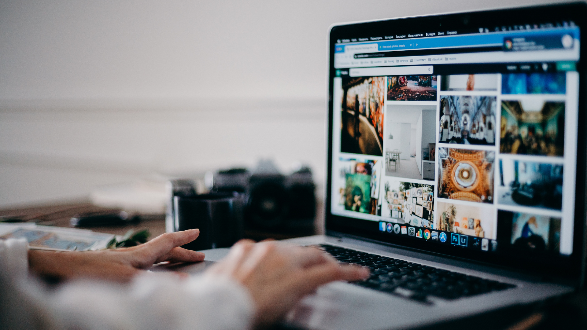 A person is typing on a laptop computer with a camera in the background.