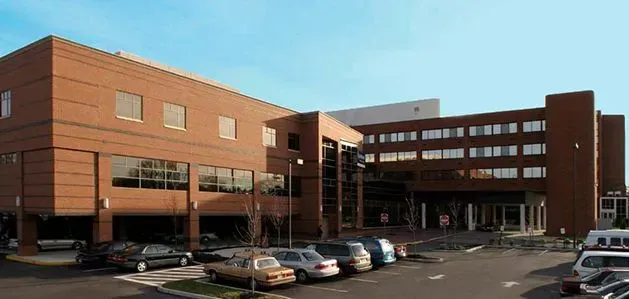 Modern brick office building with parked cars in front under a clear sky