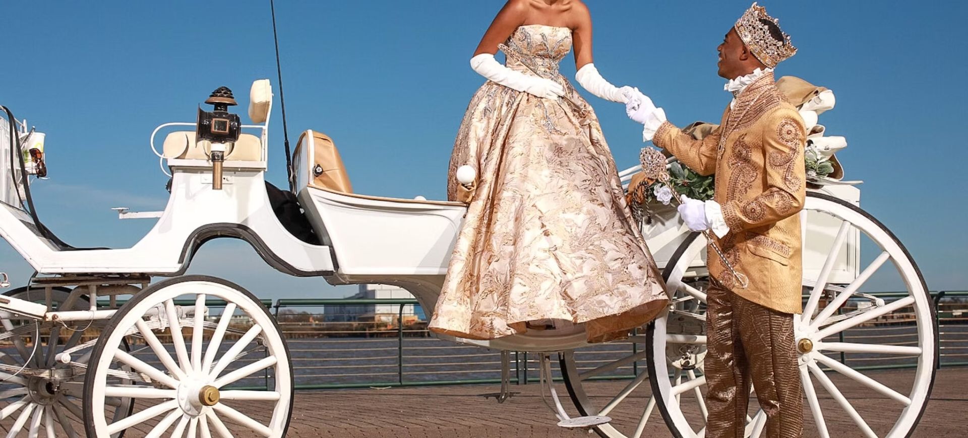 Two people by a white horse-drawn carriage on a boardwalk under a bright blue sky