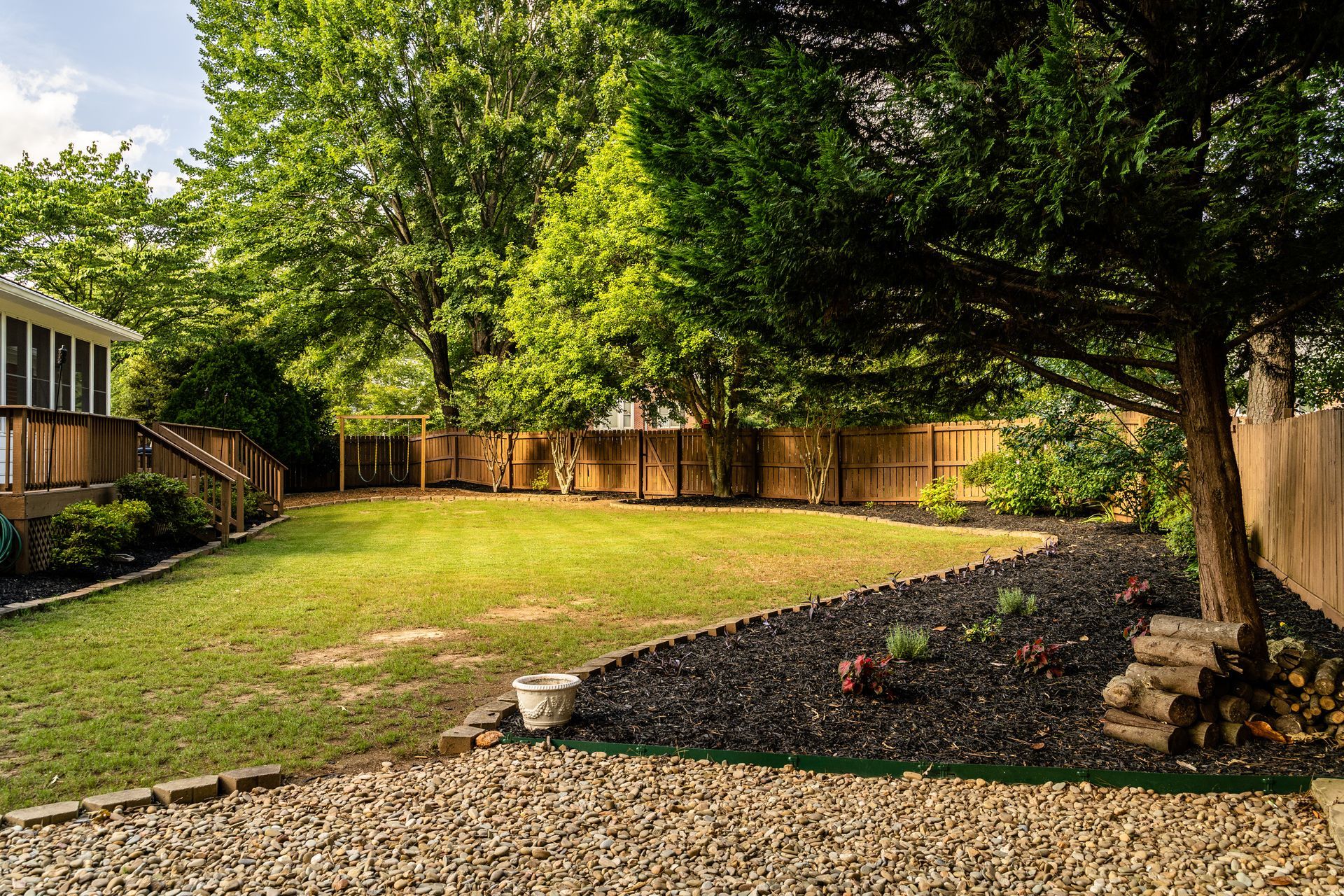Backyard with brown mulch and landscaping stone bordering a wooden fence.