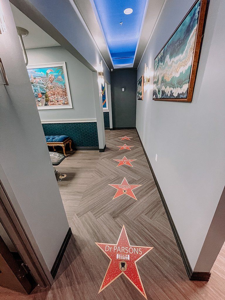 Hallway with red star floor decals, art, and a sky-like ceiling.