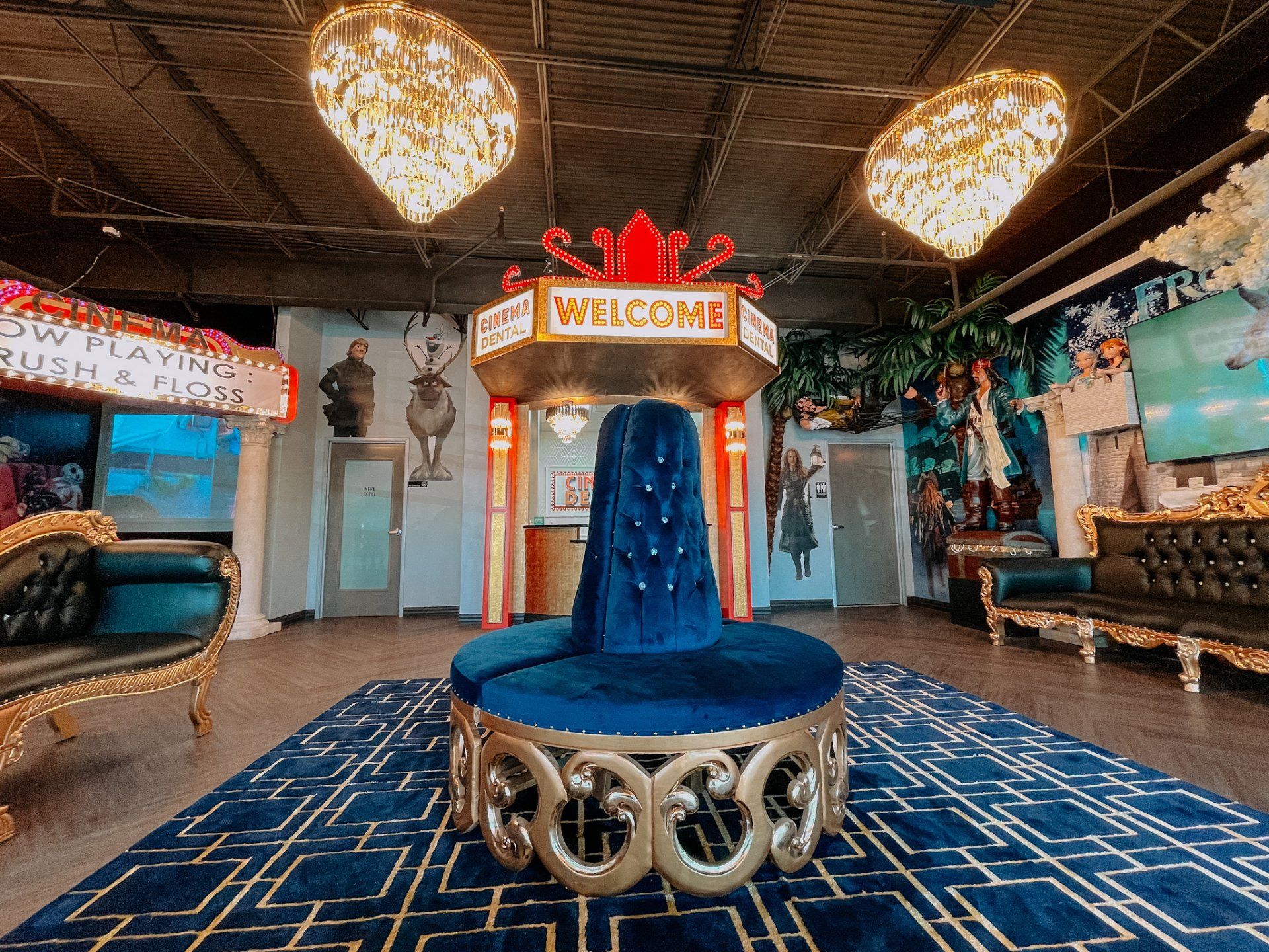 Luxurious welcome area with a blue velvet centerpiece, gold accents, and chandeliers.